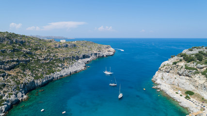 Sailing boats at the beautiful Blue Lagoon at Rhodes Island with blue clear sea water, blue sky and rocks in the water