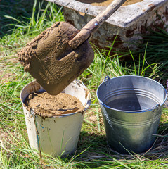 Worker with buckets of concrete at a house construction