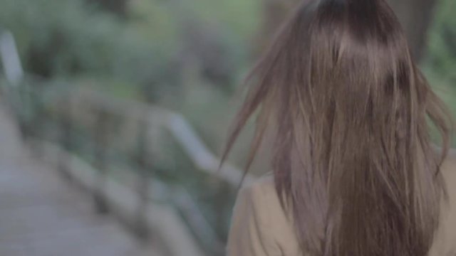Woman stepping down on outdoor stairway with brown hair at the end of the afternoon in Paris Montmartre in slow motion. Alone Girl walking down staircase in back view tracking in.