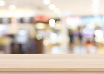 Empty brown wood table top on blur abstract background from inside shopping mall, Used for display or montage your products.