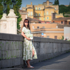 young woman posing on the bridge with city view in summer morning in Rome