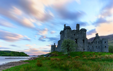 Kilchurn Castle , in the care of Historic Environment Scotland , is a ruined structure on a rocky peninsula at Loch Awe in twilight , Argyll and Bute, Scotland