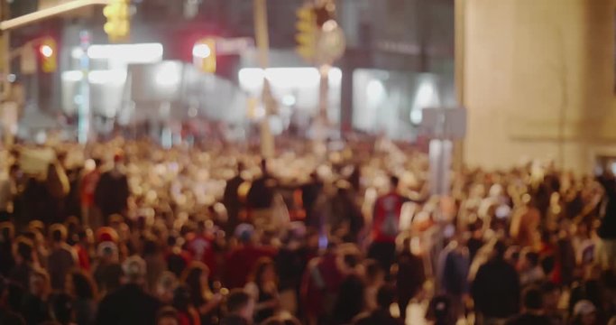 Massive defocused crowd downtown at night. Cinematic 4K footage.
