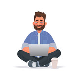 Bearded man sits on the floor and works at a laptop. Remote work via the Internet. Freelancer