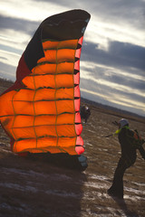 Silhouette of a skydiver with a canopy of a parachute after landing on the field in the evening illumination.  Parachute jump.