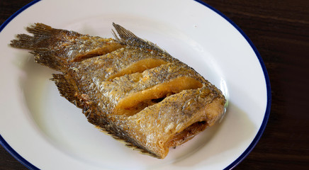 Fried dry salt fish (Thai language -pla salid) in white dish on dark background
