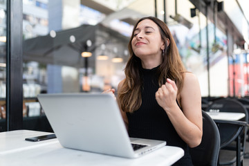 Business woman work process concept. Young woman working university project with generic design laptop. Happy excited woman at home workstation. Blurred background, film effect.