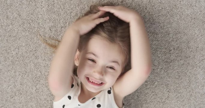 Playful little girl lying on carpet and shouting at home