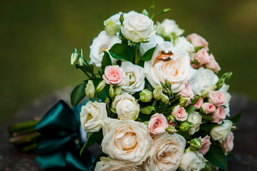 Gold wedding rings on the pink bouquet of flowers