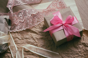 Gift box with satin ribbon. Packaging process. Wedding presents. Craft paper background. 