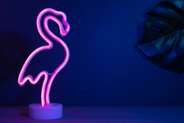 Summer pink flamingo and monstera leaf with neon pink and blue light.vacation background.