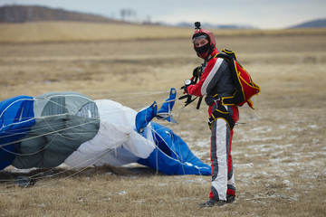 Figure skydiver with the canopy of the parachute after landing on the field. Parachute jump.