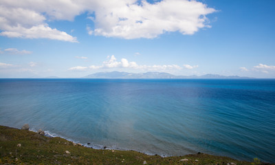 view at blue azure turquoise sea and blue sky and mountains in the horizon and white clouds in Greece Island Kos