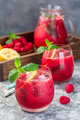 Refreshing raspberry, lemon and mint lemonade with sparkling water in a glass, vertical