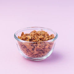 Fried onion in the glass, topping for hot dog, fast food, on a pink background, square format