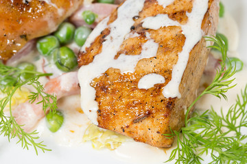 Grilled chicken fillets with bacon and peas.