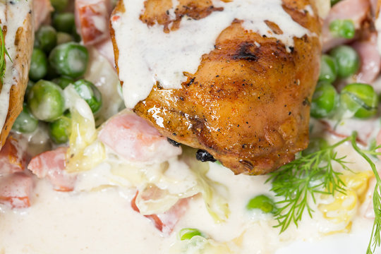 Grilled chicken fillets with bacon and peas.