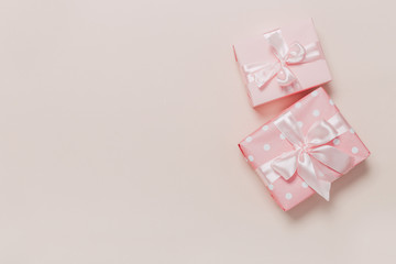 beautiful gift boxes wrapped in paper with gold and pink ribbon on a beige surface. Top view