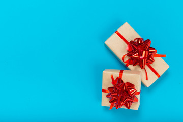 beautiful gift boxes wrapped in paper with a red ribbon and a bow on a blue surface. Top view with copy space.
