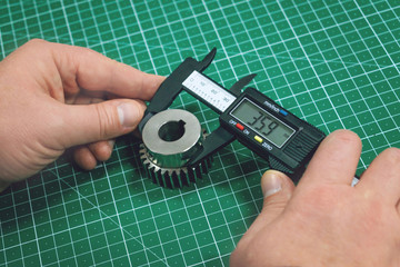 Metal gear measurement process. Factory man, worker measuring steel detail, gear with digital...