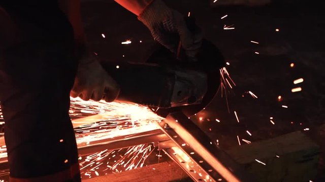 Man works circular saw in slow motion. Flies of spark from hot metal. The man's hard work. Man Chlef and smooth surface. Man worked over the steel. close-up of hand and electric saws metal. Close-up
