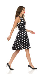 Beautiful Young Woman In Black Dotted Cocktail Dress And High Heels Is Walking