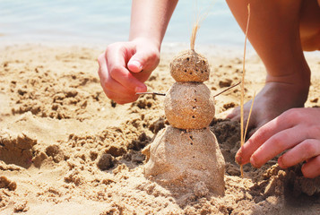 figure out of sand on the background of the river, sunglasses, flip-flops the rest of the children