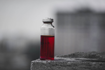 Erlenmeyer flask with red solution standing on a stone surface.