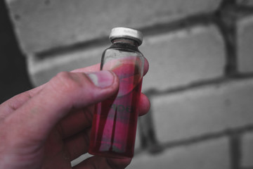Erlenmeyer flask with red solution standing on a stone surface.