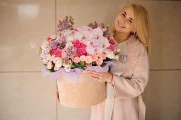 Girl holding a huge spring rose color box of tender multicolored pink flowers