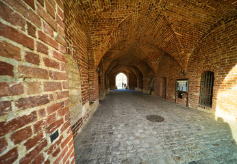 Bricked archway made of red bricks as a passage between the two wings of a medieval castle, architecture