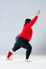 Plus size model in sportswear, fat woman doing workout on gray background, healthy lifestyle concept, body positive