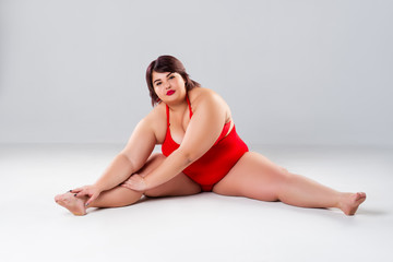 Plus size model in red lingerie, fat woman in underwear on gray background, body positive concept