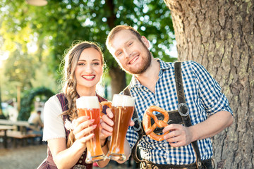 Paar in bayerischer Tracht prostet mit Weizenbier in die Kamera
