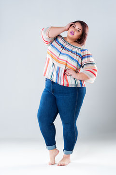 Plus size fashion model in casual clothes, fat woman on gray background, body positive concept