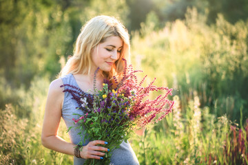 Portrait of a young beautiful woman in the nature with a bouquet of flowers.