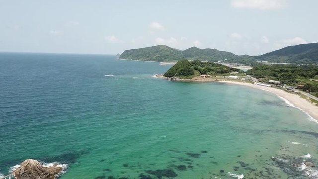 aerial footage of blue ocean, the twin rocks and the white torii gate on the water at the coast of sakurai futamigaura beach, itoshima fukuoka japan v03