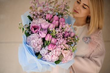 Woman in the coat holding a bouquet of purple violet tulips and lilac