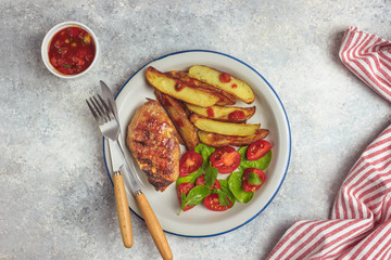 Grilled steaks, French fries and vegetables on light gray background. Top vew
