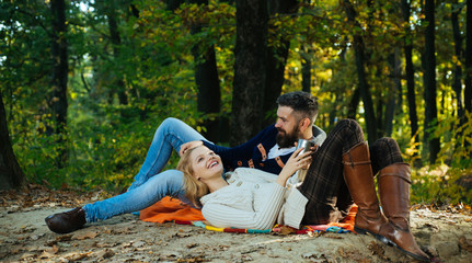 Autumn couple in love hug. Young lovers enjoying each other at a picnic. Woman lying down on the man's leg and having a romantic moment together. Beautiful autumn outside. Couple in loving.