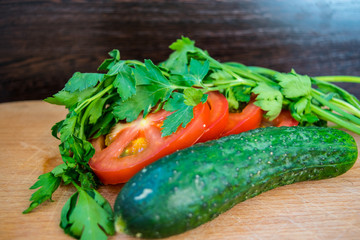 Vegetables parsley, tomatoes and cucumber on a cutting board are close-up