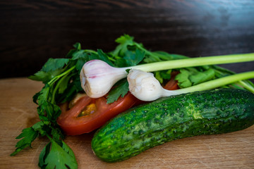 Vegetables parsley, tomatoes and cucumber, garlic are on the cutting board close-up