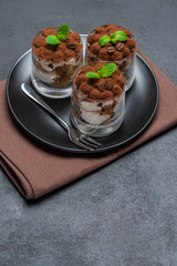 Classic tiramisu dessert in a glass on dark concrete background