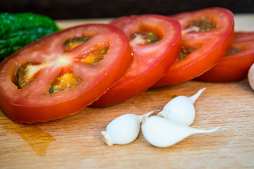 Tomato rings sliced ​​and garlic cloves on a cutting board
