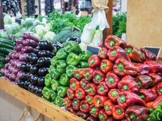 various types of well-ordered peppers and cucumbers on the shelf of a fruit shop