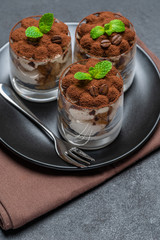 Classic tiramisu dessert in a glass on dark concrete background
