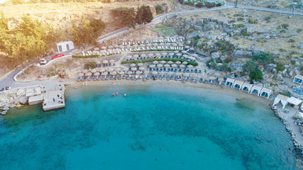 Aerial view of the amazing idyllic beach with colorful umbrellas, sunbed and people who sunbathing and swimming.