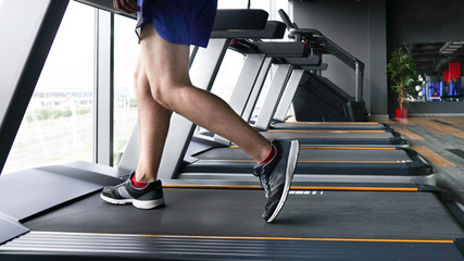 Close up shoes men's muscular legs feet running on treadmill workout at fitness gym