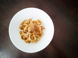 Close up of deep-fried chicken skins in a white bowl.
