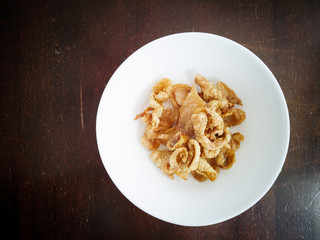 Close up of deep-fried chicken skins in a white bowl.